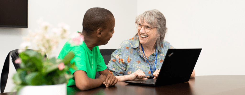 A man and a woman chat before a laptop.