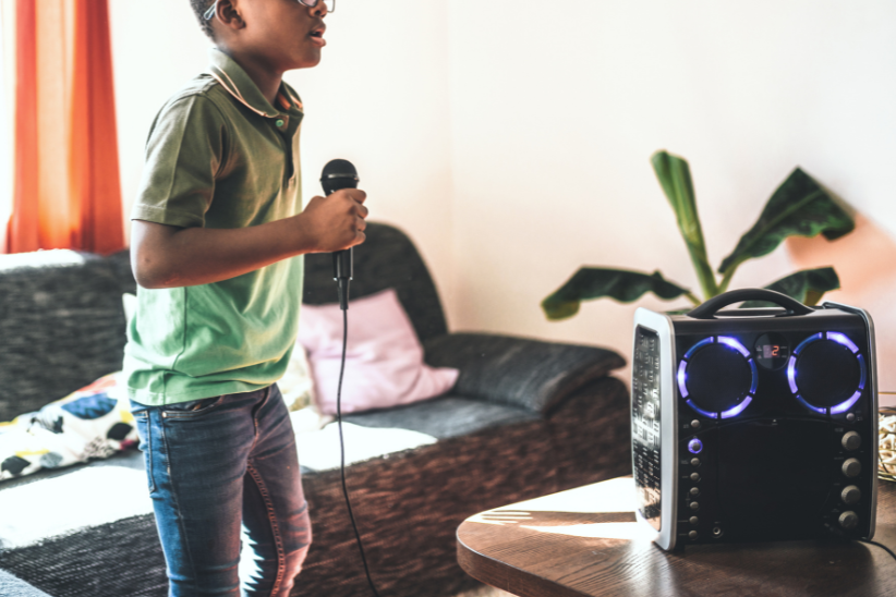 Homeless to Harmony: A young man holds a microphone by a karaoke machine in a living room.