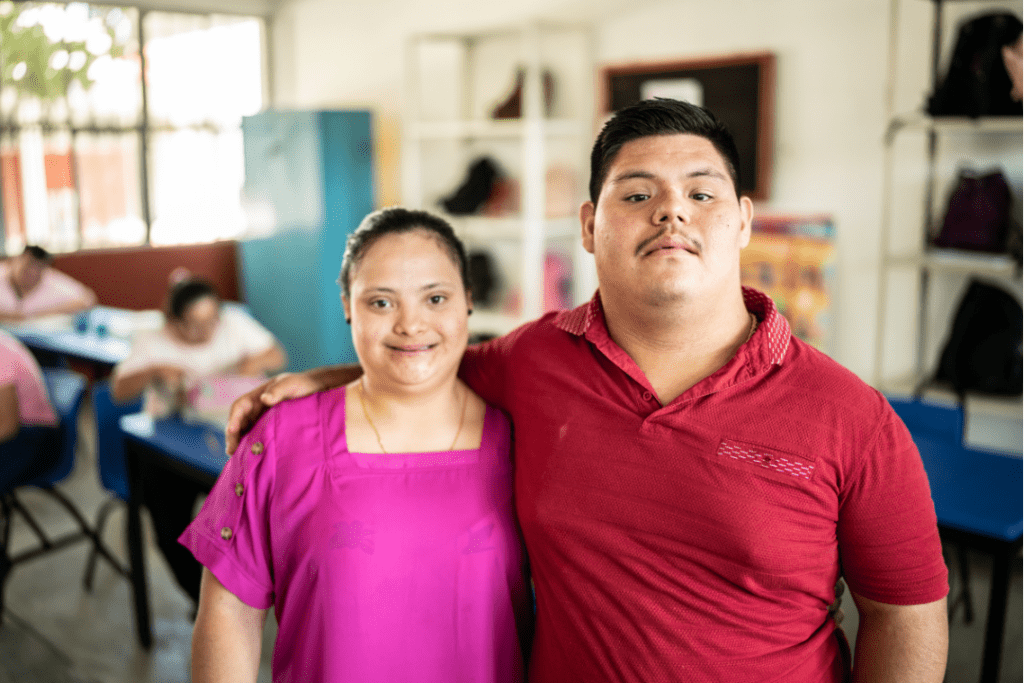 A young man has his arm around a young woman who is smiling.